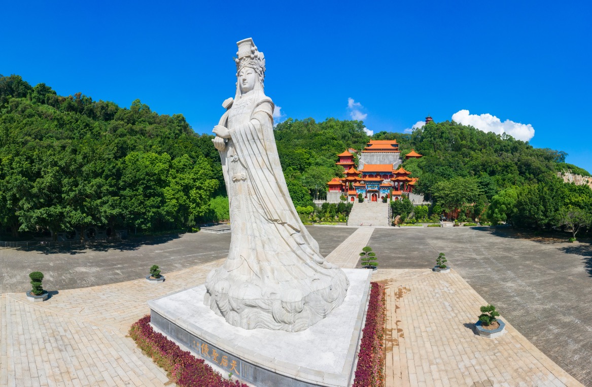 南沙天后宫位于南沙大角山东南麓，远看像一座宫殿。门前先有一座典雅的牌坊，四根立柱四句对联，横梁刻上“南沙天后宫”，旁边还有龙形浮雕，极具气势，殿前一座约5层楼高的天后像温柔地震慑四方。